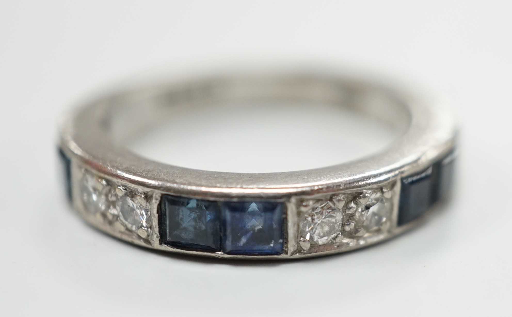 A modern 18ct white gold, six stone sapphire and four stone diamond set half eternity ring, size M, gross weight 5.2 grams.